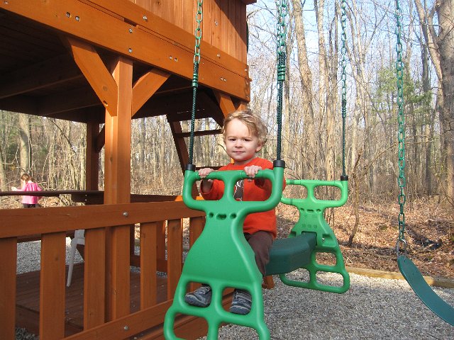 IMG_8549.jpg - Nathan's on the glider while Catherine is practicing her balancing act on the beams that border the play area.
