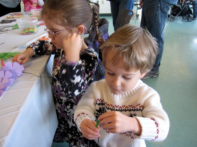 IMG_4468.jpg - The event always has crafts, games and of course an egg hunt.  Here the kids are making leis with colorful Hawaiian flower cutouts, straws and an elastic string.